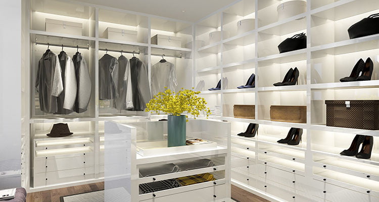 A custom walk-in closet with dark wood floors and white shelfs with back-lighting.